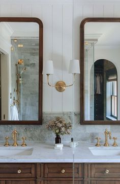 two bathroom sinks with gold faucets and marble counter tops in front of mirrors