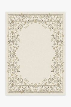 a beige and white rug with an ornate border on the bottom, surrounded by leaves