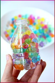 a hand holding a bottle filled with lots of gummy bears in front of a white plate