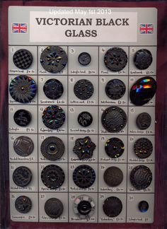 a display case filled with lots of different types of black glass buttons and magnets