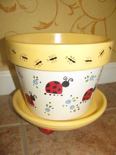 a yellow flower pot with ladybugs painted on it