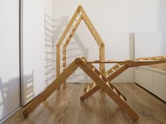 a wooden structure sitting on top of a hard wood floor next to a white wall