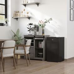 a kitchen with white walls and wooden flooring next to a black refrigerator freezer