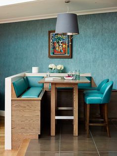 a dining room table with two blue chairs and a painting on the wall above it