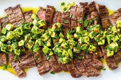 steak with avocado and salsa on a white platter, ready to be eaten