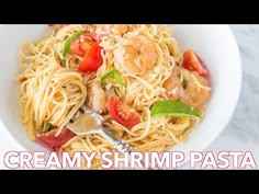 a white bowl filled with pasta and shrimp on top of a marble counter next to a fork