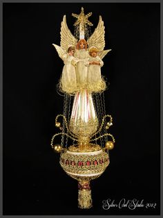 an angel figurine on top of a gold pedestal with beads and chains around it