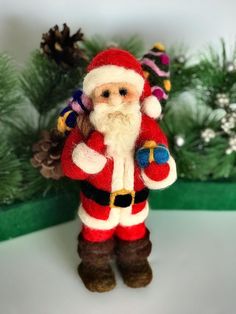 a santa clause figurine is standing in front of some pine branches