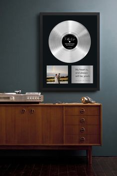 a record player sitting on top of a wooden cabinet next to a wall mounted album