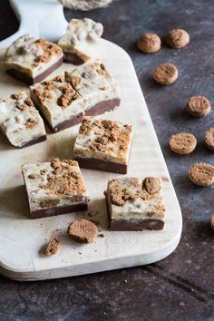 several pieces of cake sitting on top of a wooden cutting board next to some cookies