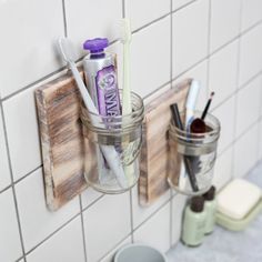 two toothbrushes are in a jar on the wall