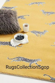 a yellow rug with giraffes on it next to a cup of coffee