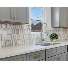 a kitchen with gray cabinets and white counter tops, gold pulls on the faucet