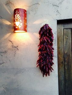 a wall mounted light next to a door with a plant hanging from it's side