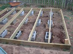 a wooden frame with cinder blocks in the middle and dirt on the ground next to it