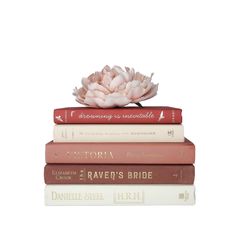 three books stacked on top of each other with a pink flower in the middle one