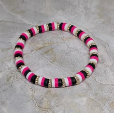 a pink and black beaded bracelet sitting on top of a table