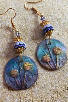 These Ceramic Earrings are made with charms made by an artisan.  The earrings are accented with ceramic and metal flower bead caps and Swarovski crystals Artistic Dangle Earrings, Artistic Handmade Flower Earrings, Handmade Artistic Flower Earrings, Artisan Dangle Flower Earrings, Unique Soldered Drop Earrings, Artistic Teardrop Soldered Earrings, Bohemian Hand Painted Purple Earrings, Purple Artisan Earrings With Dangling Beads, Bohemian Purple Flower Earrings