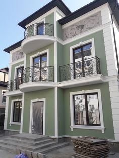 a green and white two story house with balconies