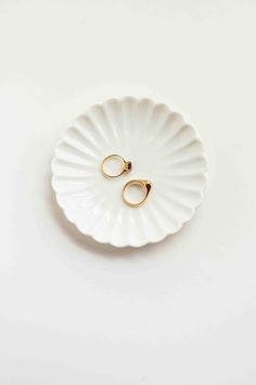 two gold wedding rings sitting on top of a white plate