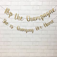 a white brick wall with gold foil lettering that says, top the champagne she's changing her name