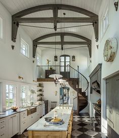 a large kitchen with an island in the middle and a spiral staircase to the second floor