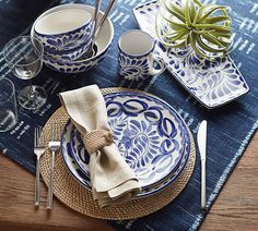 a place setting with blue and white plates, silverware, and succulents