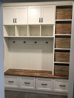 a room with white cabinets and baskets on the wall