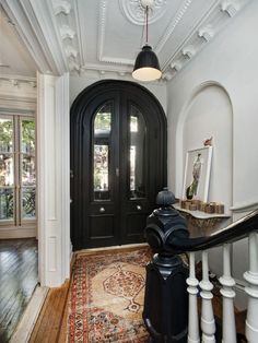 an entryway with black doors and white trim on the walls, wood floors and rugs