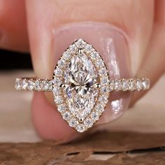 a woman's hand holding an engagement ring with a pear shaped diamond in the center