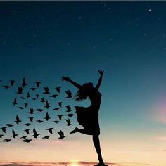 a woman standing on top of a hill under a sky filled with birds