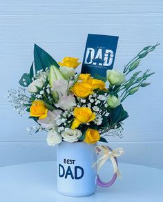 a bouquet of yellow and white flowers in a blue mug with a dad's day card