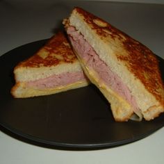 two grilled sandwiches on a black plate sitting on a white counter top next to each other