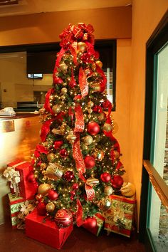 a christmas tree with red and gold ornaments in an office lobby decorated for the holidays