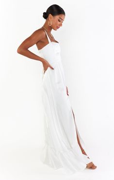 a woman is wearing a white dress and standing in front of a white background with her hands on her hips