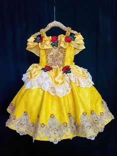 a yellow and white dress with roses on the collarline is hanging from a rope