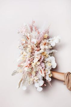 a bouquet of flowers is being held up by someone's hand on a white background