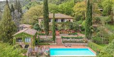 an aerial view of a house with a pool in the foreground and trees surrounding it