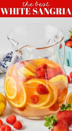 a pitcher filled with water and fruit next to lemons, strawberries and raspberries