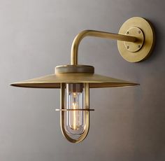 an outdoor wall light with a clear glass shade on the side and a metal arm