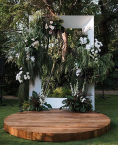 a wooden platform with flowers and greenery on it in the middle of a yard