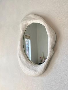 a mirror that is on the side of a wall in a room with white walls