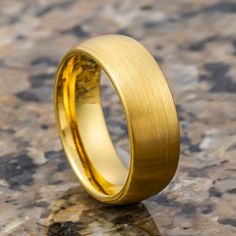 a yellow gold wedding ring sitting on top of a marble surface