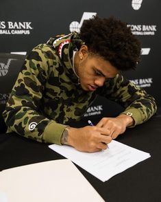 a young man sitting at a table signing papers