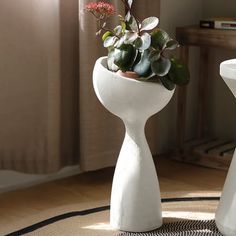 a white vase with some plants in it