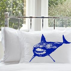 a bed with two white pillows and a blue shark pillow