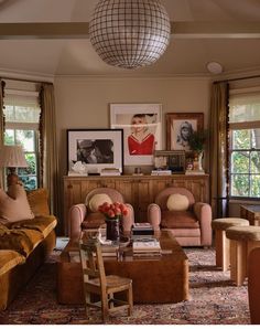 a living room with couches, chairs and pictures on the wall in it's center