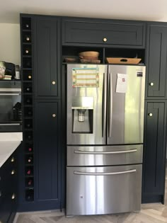 a metallic refrigerator freezer sitting inside of a kitchen next to black cupboards and drawers