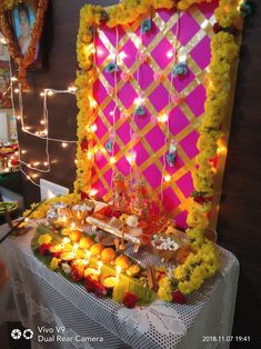 a decorated table with flowers and candles on it in front of a pink screen wall