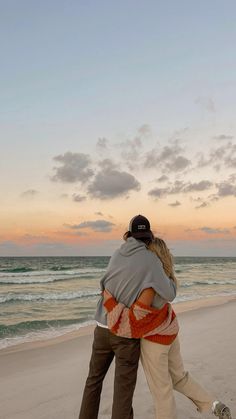 two people hugging each other on the beach